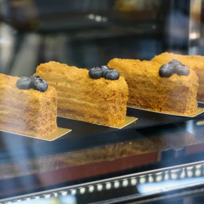 Plakken honey cake met bosvruchten in de vitrine van Patisserie La